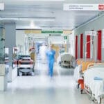 hospital hallway with beds and a nurse