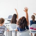 children raising hands in a classroom