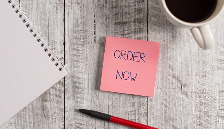 Handwriting text Order Now. Concept meaning the activity of asking for goods or services from a company Stationary placed next to a cup of black coffee above the wooden table.