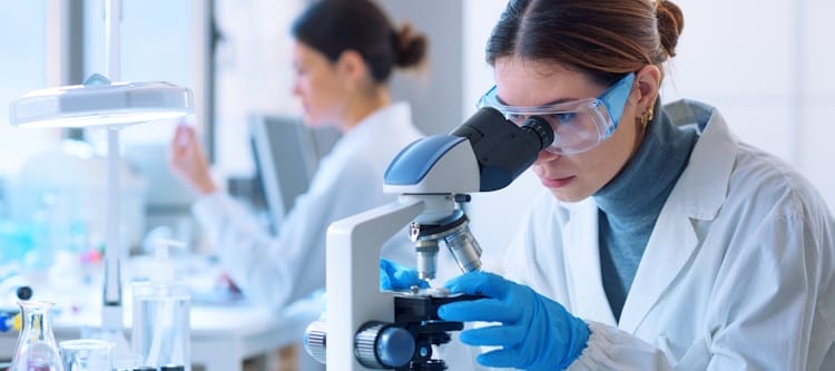 tech using microscope at pharmaceutical lab